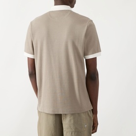Model wearing Farah Vintage Clement Logo Contrast Collar Polo Shirt in Stone Grey, shown from the back, with white contrast collar and sleeve trims.