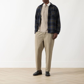 Model wearing Farah Vintage Clement Logo Contrast Collar Polo Shirt in Stone Grey, styled with navy plaid overshirt and beige trousers.