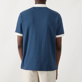 Model wearing Farah Vintage Clement Logo Contrast Collar Polo Shirt in Aegean Blue, rear view, with cream contrast collar and sleeves.