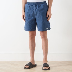 Model wearing Farah Vintage Edgar Logo Textured Swim Shorts in Soft Green with elasticated waist and embroidered logo, styled with dark slides.