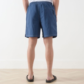 Model wearing Farah Vintage Edgar Logo Textured Swim Shorts in Soft Green, rear view showing zip back pocket and elasticated waistband, styled with