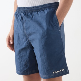 Model wearing Farah Vintage Edgar Logo Textured Swim Shorts in Soft Green with elasticated waistband, contrast stitching and embroidered logo detail.
