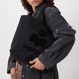 Model carrying Isabel Marant Yenky-GZ Small Tote Bag in black canvas with tonal logo print, styled with grey denim jacket