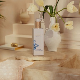 Rituals Hand Balm in white pump bottle with blue floral detail, styled with ceramic vase and white tulips on stone surface