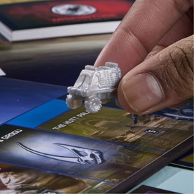 Hand holding a Razor Crest token from Board Games Star Wars: The Mandalorian and Grogu Monopoly, with game board visible below.