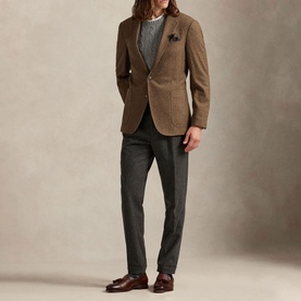 Model wearing a brown textured blazer with grey trousers, striped top, pocket square, and brown loafers