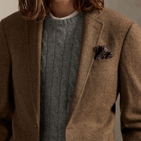 Model wearing tan wool blazer with grey cable-knit sweater and floral pocket square