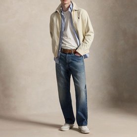 Model wearing Ralph Lauren New Stone casual jacket, styled with blue shirt, denim jeans, brown belt and white trainers.