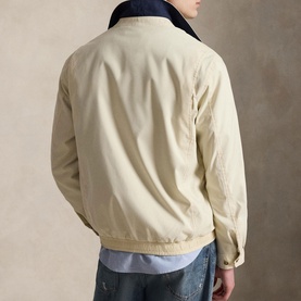 Model wearing Ralph Lauren casual jacket in New Stone with navy collar, styled with blue jeans and chambray shirt, rear view.