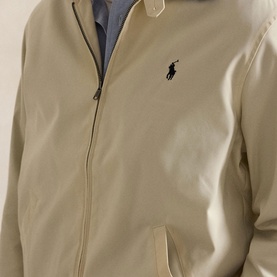 Model wearing Ralph Lauren casual jacket in New Stone, zip-up with polo pony logo, blue check lining visible at collar.