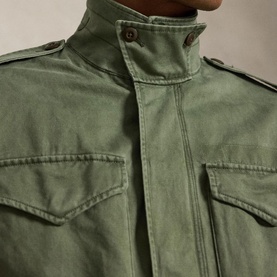 Model wearing Ralph Lauren mint olive casual jacket, close-up of chest pockets, epaulettes, and button-fastening funnel neck detail.