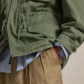 Model wearing Ralph Lauren Mint Olive casual jacket, styled with a light blue shirt and tan houndstooth trousers. Close-up of waist detail.