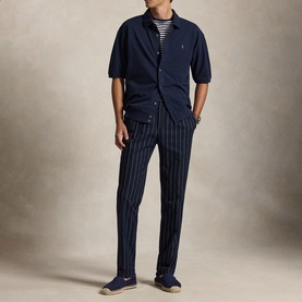 Model wearing navy short-sleeve button-up shirt, styled with navy pinstripe trousers, striped tee, and navy espadrilles.