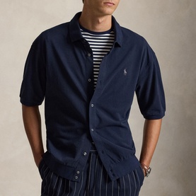 Model wearing navy short-sleeve button-up shirt with embroidered pony logo, styled with striped T-shirt and pinstripe trousers