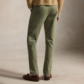 Model wearing Ralph Lauren sage green chino trousers, rear view, styled with a cream knit and brown leather loafers.