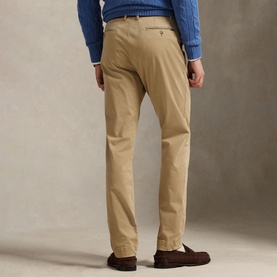 Model wearing Ralph Lauren khaki chino trousers, rear view, styled with a blue cable-knit sweater and brown loafers.