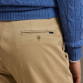 Model wearing Ralph Lauren khaki chino trousers, close-up of rear pocket detail, styled with a blue cable-knit jumper.