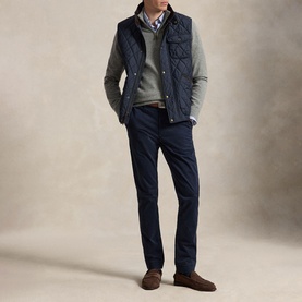 Model wearing navy quilted gilet over grey sweater and check shirt, styled with navy trousers and brown suede loafers