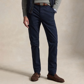 Model wearing navy slim-fit chino trousers, styled with a grey knit, brown belt and brown loafers