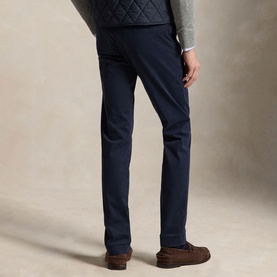Model wearing navy slim-fit chinos, styled with a grey quilted gilet and brown suede loafers, rear view