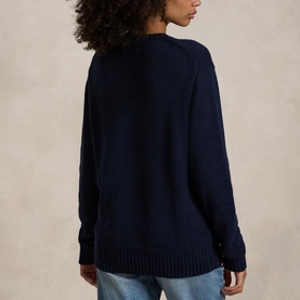 Model wearing navy blue knit crewneck sweater with ribbed hem and cuffs, styled with light blue jeans, back view