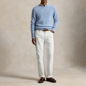Model wearing a light blue cable-knit crew-neck sweater, styled with white jeans, a white shirt, brown belt and dark brown loafers.