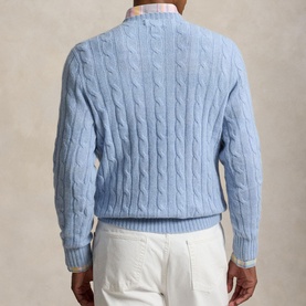 Model wearing light blue cable-knit crew neck sweater, styled with white trousers and collared shirt, rear view