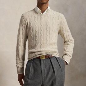 Model wearing cream cable-knit crew-neck sweater, styled with white collared shirt, brown leather belt and grey tailored trousers