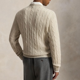 Model wearing oatmeal cable-knit crew neck jumper, styled with white shirt and grey trousers, rear view