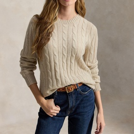 Model wearing cream cable-knit crew-neck sweater, styled with dark blue jeans and a brown leather belt.