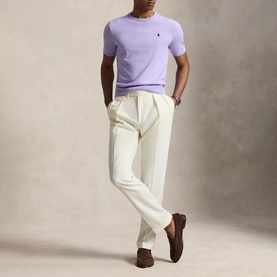 Model wearing Ralph Lauren Powder Purple knit crew neck T-shirt with cream trousers and brown suede loafers.