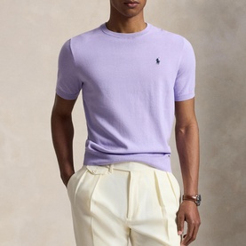 Model wearing Ralph Lauren powder purple knit crew neck tee with cream tailored trousers and a watch.
