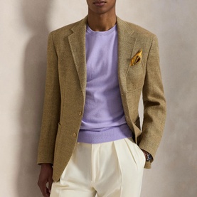 Model wearing Ralph Lauren Powder Purple crew neck knit, styled with a tan blazer, gold pocket square, and cream trousers.