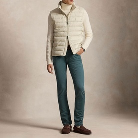 Model wearing Ralph Lauren Basic Sand quilted gilet over cream roll-neck, styled with teal trousers and brown suede loafers.