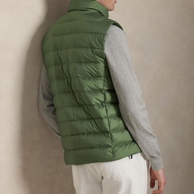 Model wearing Ralph Lauren green quilted down gilet, styled with grey knit sweater and white trousers, rear view