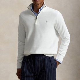 Model wearing Ralph Lauren Deckwash White half-zip knit, styled with blue stripe trousers and Oxford shirt collar visible at neck.