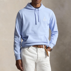 Model wearing Ralph Lauren pebble blue pullover hoodie with chest logo, styled with white trousers and woven leather belt.
