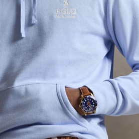 Model wearing Ralph Lauren Pebble Blue hoodie with gold logo detail, styled with a brown leather strap watch with blue dial.