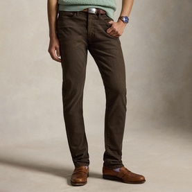 Model wearing Ralph Lauren circuit brown slim-fit jeans, styled with a green jumper, leather belt, and tan loafers.