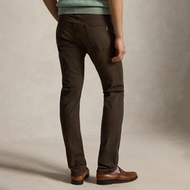 Model wearing Ralph Lauren circuit brown jeans, styled with a mint green sweater and tan leather loafers, rear view.