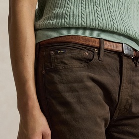 Model wearing Ralph Lauren circuit brown jeans, styled with a sage green cable-knit jumper and brown leather belt.