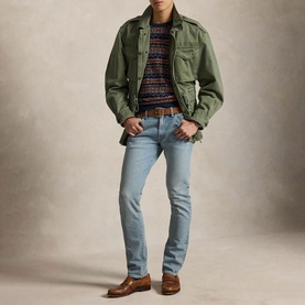 Model wearing Ralph Lauren blue slim-fit jeans styled with a green military jacket, navy fair isle sweater, and brown leather loafers.