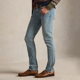 Model wearing Ralph Lauren blue slim-fit jeans with brown leather belt, styled with a patterned knit jumper and tan loafers.
