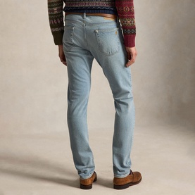 Model wearing Ralph Lauren blue slim-fit jeans, rear view, styled with a patterned knit jumper and brown leather shoes.