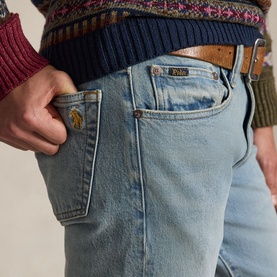 Model wearing Ralph Lauren blue jeans with embroidered logo pocket, styled with a tan leather belt and multicoloured knit sweater