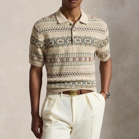 Model wearing cream Fair Isle knit polo shirt with multicolour geometric pattern, styled with white trousers and brown belt