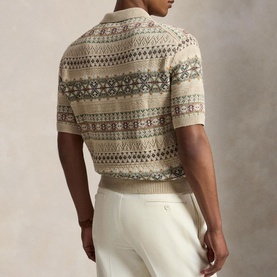 Model wearing a fair isle knit short-sleeve polo in neutral tones, styled with white trousers, rear view shown.