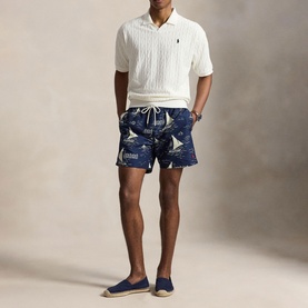 Model wearing Ralph Lauren white cable-knit polo shirt, styled with navy nautical-print swim shorts and navy espadrilles.