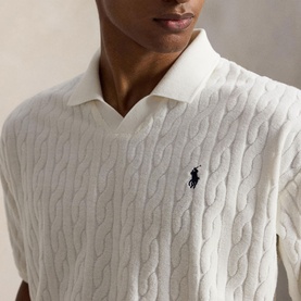 Model wearing Ralph Lauren white cable-knit polo shirt with open collar and navy embroidered pony logo, close-up crop view.