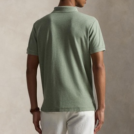 Model wearing Ralph Lauren polo shirt in Greenery Heather, short sleeves, piqu&eacute; texture, back view, styled with white trousers.